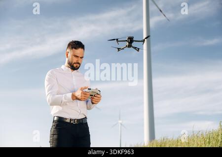 Controlling the drone. Engineer in field checking on wind turbine production. Stock Photo