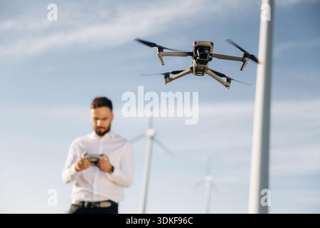 Controlling the drone. Engineer in field checking on wind turbine production. Stock Photo