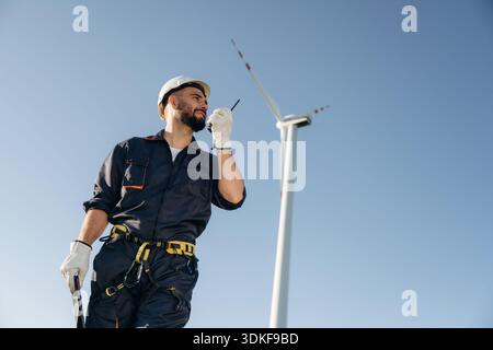 Using walkie talkie. Engineer in field checking on wind turbine production. Stock Photo