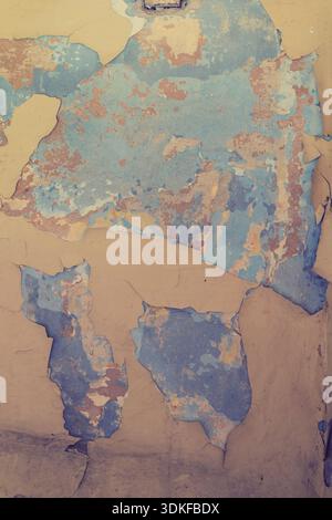 Old wall showing distressed surface with crumbling beige and blue paint Stock Photo