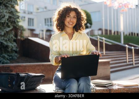 Beautiful woman student is near the university outdoors. Stock Photo