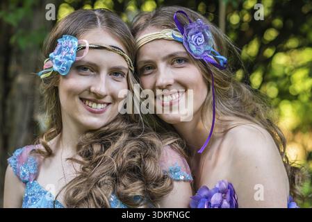 Closeup portrait happy smiling sisters twins in the garden Stock Photo