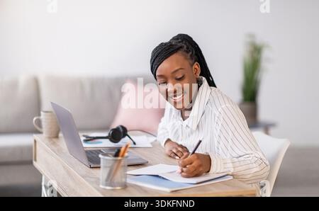 Pretty black woman student studying in front of laptop Stock Photo
