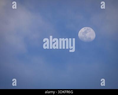 Almost full moon glowing on a blue evening sky Stock Photo