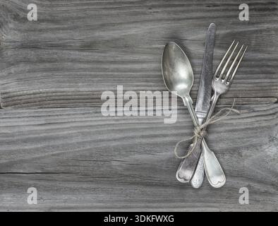 Crossed vintage fork, table knife and spoon on old wooden boards Stock Photo
