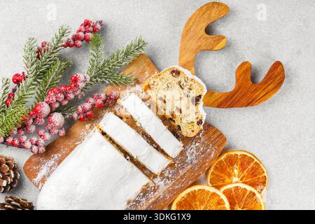 Traditional Christmas stollen, sweet fruit loaf sliced on wooden board, dusted with powdered sugar on white textured background. Spices, dried fruits Stock Photo