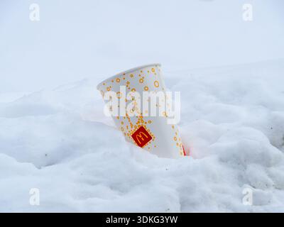 McDonald's paper cup in the snow with a playful, minimalist design of orange and yellow circles, which represents fizz or bubbles Stock Photo