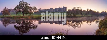 A panoramic view at dusk of Alnwick Castle in Northumberland reflected in the river Aln as seen from the Pastures with lovely reflections and a clear Stock Photo