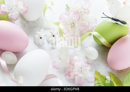 Beautiful delicate Easter composition with pink cherry flowers, multicolored Easter eggs, Easter bunny and butterfly on the stone background Stock Photo