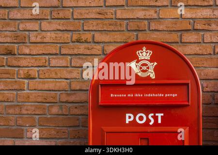A red danish postbox on a brick wall. The letters must not contain money, Frederikssund, Denmark, 30 mars, 2018 Stock Photo