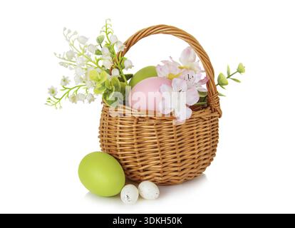 Wicker basket with pink and green Easter eggs as well as with lilies of the valley and other flowers isolated on white background Stock Photo