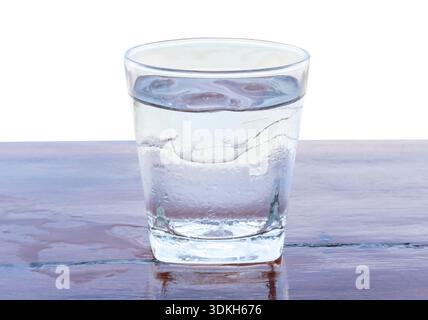 Drinking water with ice cubes in glass served on table is isolated on white background with clipping path. Stock Photo