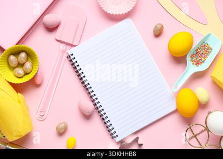 Blank notepad for recipes with Easter eggs and baking tools on pink background Stock Photo