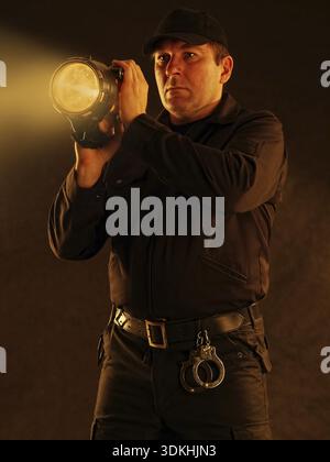 Policeman with lit torch searching the area Stock Photo