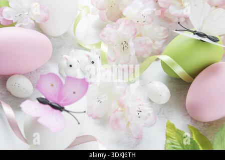 Beautiful delicate Easter composition with pink cherry flowers, multicolored Easter eggs, Easter bunny and butterfly on the stone background Stock Photo