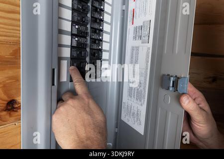 Close up of a home owner inspecting the electrical breakers or fuse box to restore power. Stock Photo