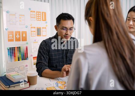 A group of UX/UI designers brainstorming creative ideas together, discussing color palettes and layout concepts for a new mobile application interface Stock Photo