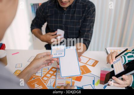 A group of UX/UI designers brainstorming creative ideas together, discussing color palettes and layout concepts for a new mobile application interface Stock Photo