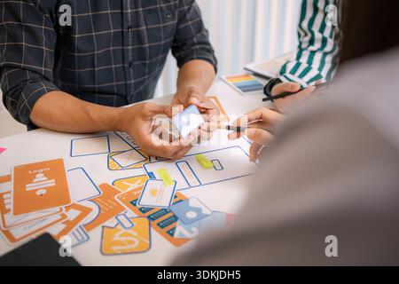 A group of UX/UI designers brainstorming creative ideas together, discussing color palettes and layout concepts for a new mobile application interface Stock Photo