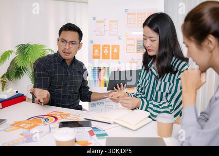 A tense business meeting where a team discusses design problems and project challenges. The man tries to explain solutions while one team member looks Stock Photo