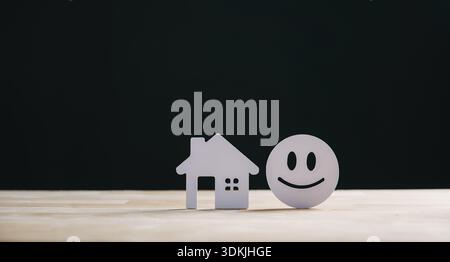 Real estate customer satisfaction home house concept shown by paper property model and happy face, representing best client reviews and feedback on co Stock Photo
