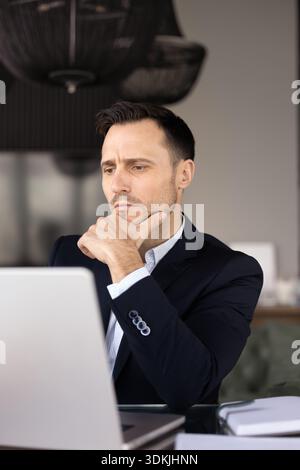 Focused Latin business leader man sitting at laptop Stock Photo