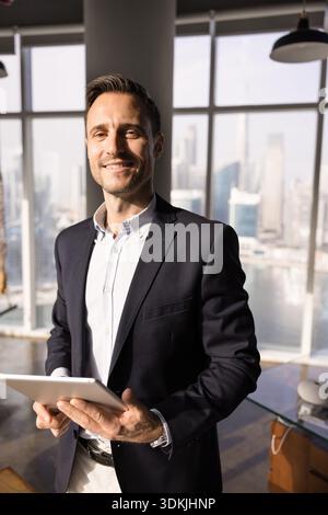 Positive young Hispanic executive man holding tablet Stock Photo