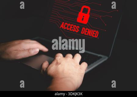 Hands typing on laptop with red Access Denied warning screen, concept of cybersecurity, hacking prevention, data breach alert, and online security pro Stock Photo