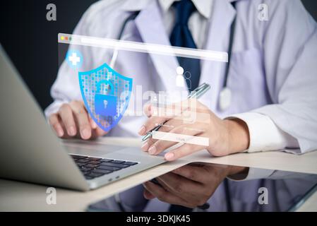 Doctor using laptop with holographic shield and lock, representing healthcare cybersecurity, patient data protection, EHR security, and digital health Stock Photo