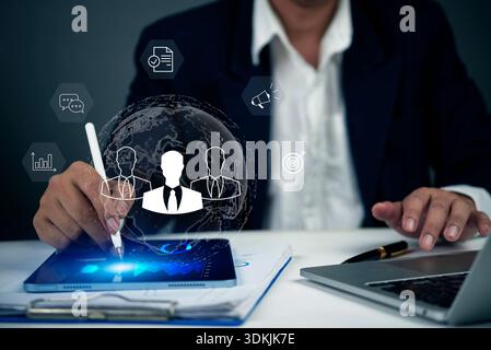 Digital business strategy concept with hologram icons of team, target, analytics, and communication. Man in suit using tablet for HR management, corpo Stock Photo