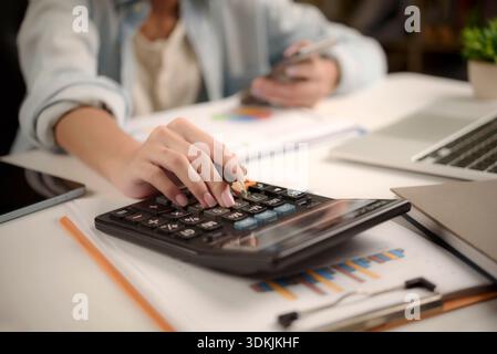 businesswoman using a calculator and analyzing business charts and graphs on desk. financial management, tax planning, and strategic budget analysis. Stock Photo