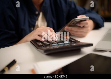 woman is calculating expenses and checking data smartphone working from home. modern financial management, business, and online shopping, perfect for Stock Photo
