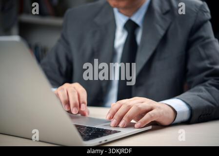 Close-up of male executive hands using laptop touchpad at office desk, professional manager in formal wear analyzing data, sending emails, or managing Stock Photo