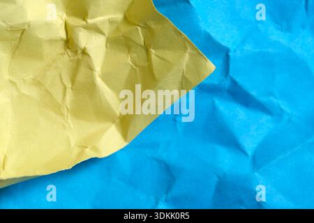 Wrinkled yellow and blue paper intertwine, creating a lively, textured scene. Stock Photo