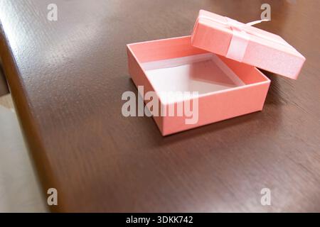 Open pink gift box with ribbon lid on wooden surface background Stock Photo
