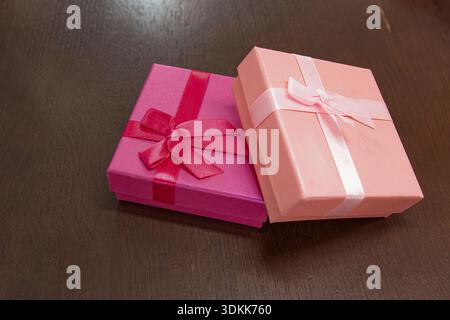 Two pink gift boxes with ribbon bows on dark wooden surface with copy space Stock Photo