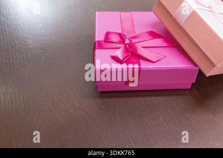 Two pink gift boxes with ribbon bows on dark wooden surface with copy space Stock Photo