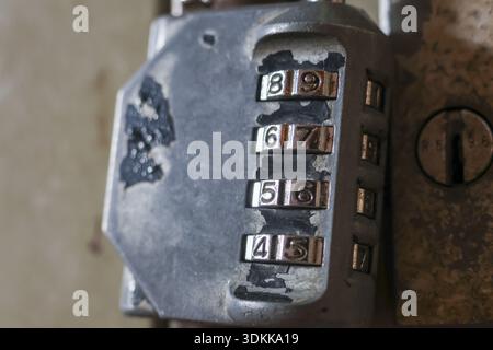 Close up of an old, weathered metal combination lock with rusty, forgotten secret code. This grunge padlock represents mysterious challenge for securi Stock Photo