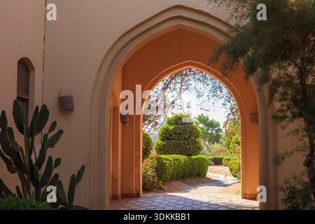 A large archway with a path leading through it. The archway is made of stone and the path is made of bricks. The archway is open to the sky and the pa Stock Photo