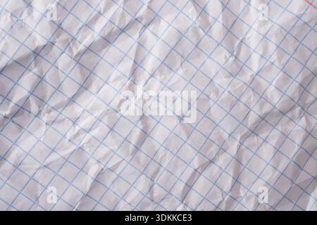 Crumpled white paper with blue grid lines provides textured background Stock Photo