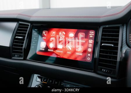 Close up of Apple CarPlay infotainment system displayed on a modern car dashboard showing navigation music and messages enabling connected driving con Stock Photo