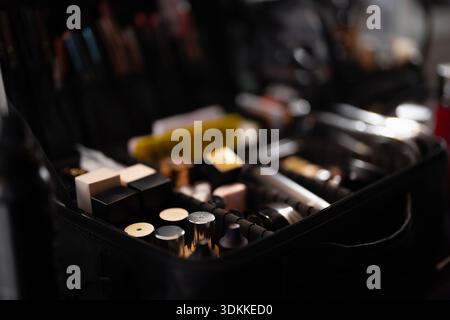Beauty preparation scene showing open makeup bag with palettes, lip products and brush set, selective focus on tools and containers in professional ba Stock Photo