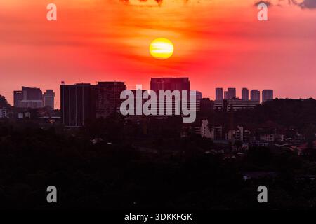 Vibrant orange sunset sky glowing behind silhouetted Kuala Lumpur city buildings Stock Photo