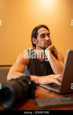 Male content creator working on laptop with camera Stock Photo