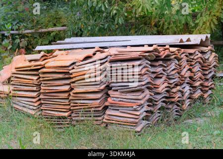 Roof tiles. Ceramic roofing tiles stacked in yard. Pile of terracotta colored tiles. Traditional building material. Stock Photo