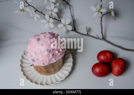 Top view of a traditional Easter cake (kulich) surrounded by three decorated eggs and a blooming almond branch. Spring holiday composition suitable fo Stock Photo