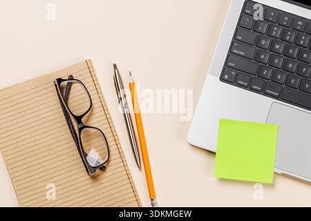 Laptop and stationery on beige workspace, top view with copy space, minimal office background Stock Photo