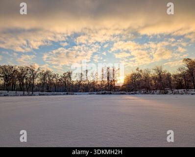 Sunset with orange clouds over a frozen winter lake Stock Photo