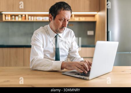 Tired businessman working overtime late on laptop computer at home office, selective focus Stock Photo