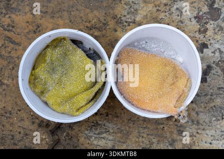 Two dishwashing sponges in plastic bowls with detergent on a gray concrete floor. A clear concept of manual cleaning, household chores, domestic hygie Stock Photo